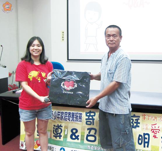 「打開家門~讓愛住進來」金門家扶中心下鄉宣導兒少保護及寄養家庭招募。首場假水頭村舉辦,社工代表致贈宣導品並由社區理事長黃延良(右)代表接受。(金門家扶中心提供)