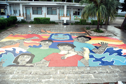 賢庵國小垵湖分校外籍教師孔輝和學生一同在校園地上彩繪大幅的作品，將留給學校一塊醒目的新地標。
（垵湖分校提供）