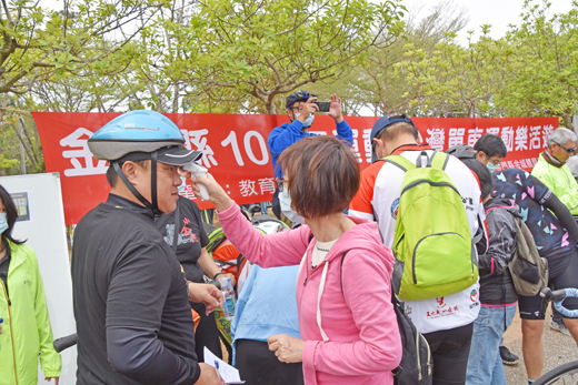 配合縣府防疫政策及措施,報到車友一一量測體溫、噴酒精消毒。(李金鎗攝)