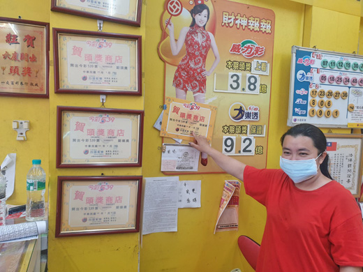 店員開心展示店內開獎紀錄。(許峻魁攝)