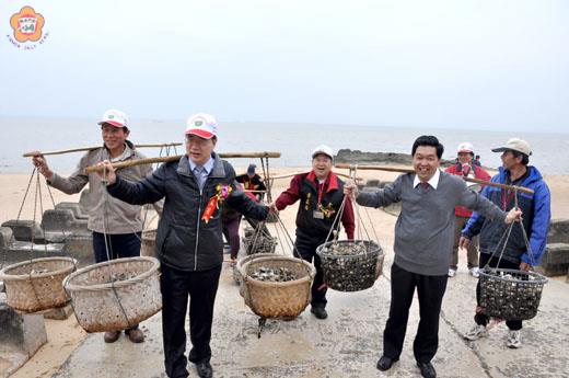 古寧頭蚵民子弟的縣長李沃士(前左)、和金寧鄉長陳成勇(右)帶頭挑蚵,傳達討海人風雨無阻的勤勞精神。(許加泰攝)v