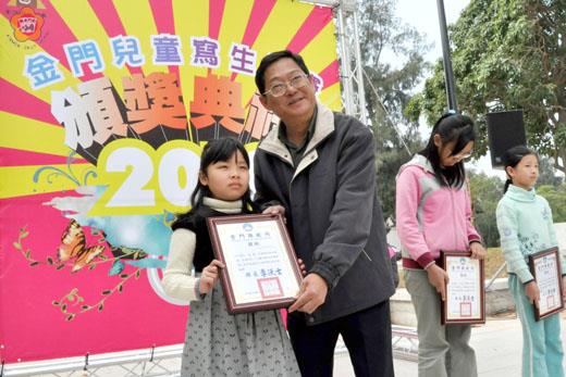 金門縣文化局辦理「2010金門兒童寫生比賽」,文化局長李錫隆頒獎表揚績優得獎學生,並分別與他們合照。(莊煥寧攝)