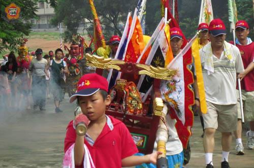   塔后「忠義廟」醮慶，小二生盛俊豪（前）荷著碧虎千歲的小轎出社。（張建騰攝）