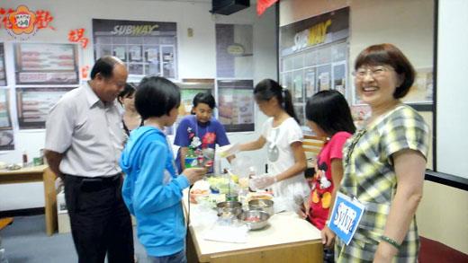   烈嶼鄉公所「暑期兒童英語研習營」的結業式活動，邱英美、呂曉娟兩位老師把教室場景虛擬成外國速食餐廳，鄉長洪成發開心看到小朋友體驗用英語點餐，運用所學。（許加泰攝）