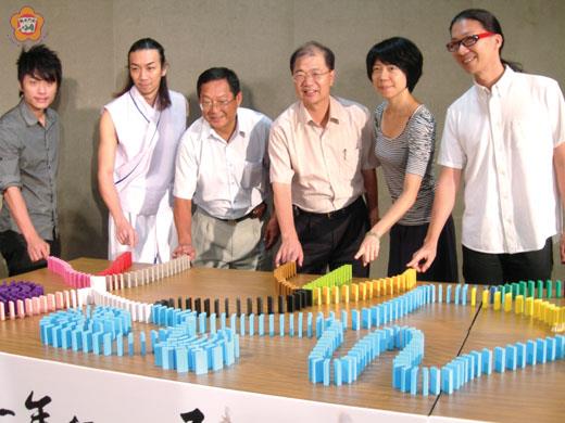   縣長李沃士與金門和平藝術季表演團體代表一同推倒骨牌，揭開一連二個月的活動序幕。（金門縣政府台北服務處主任陳永富提供）