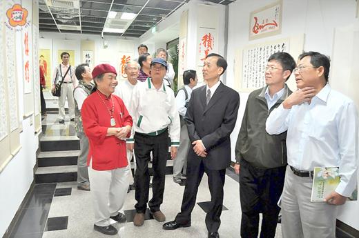 國防部後備司令部榮譽顧問黃登貴、金門縣書法學會「大漢隸法書法展」昨聯合開幕， 黃登貴（圖左）向來賓介紹他的創作。參展書法學會成員，欣賞也推崇張奇才的作品。
（陳麗妤攝）