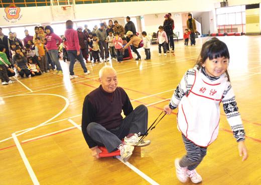   沙幼親子運動會的「超級大力士」活動是由家長坐上圓形滑板車，再由小朋友拖著車子進行接力。（張建騰攝） 