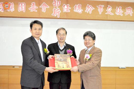 金門縣長李沃士（中）監交之下，救國團金門縣團委會卸任總幹事鄧效忠（左）和新任總幹事王群元（右）完成工作交接，與會觀禮貴賓給予祝福。（楊水詠攝）